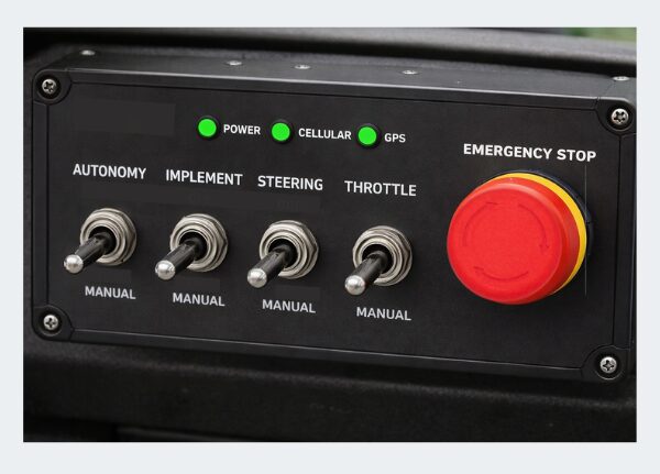 On-cab control panel for an autonomous tractor with mode selection toggles, status LEDs, and NKK's red emergency stop pushbutton with directional arrows legend for local stop control.